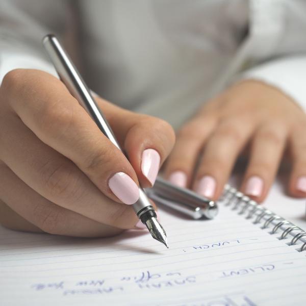 Photo of a person's hand writing in a notebook